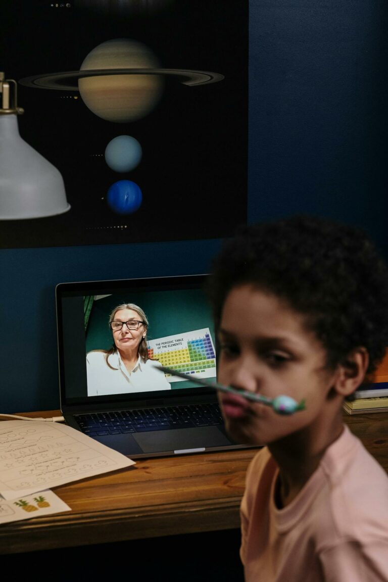 Child engaged in an online class with a teacher on a laptop, fostering education.