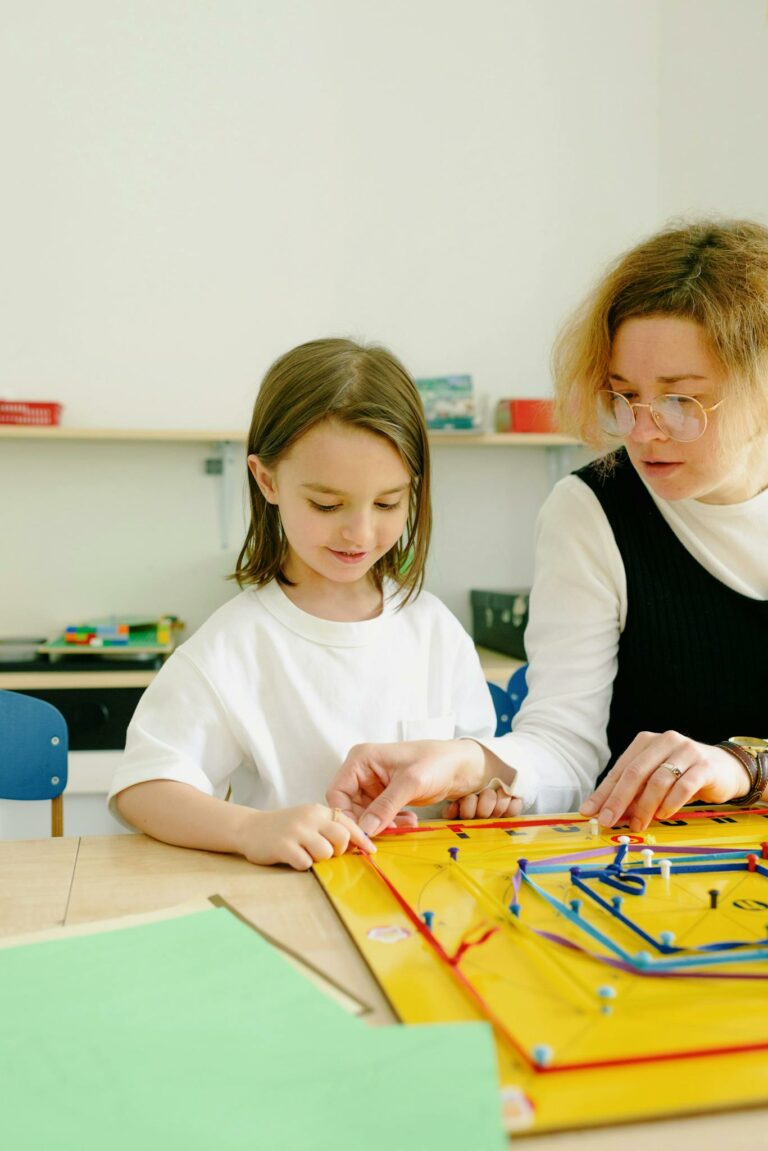 Young girl learning with teacher at a table, using an educational board game indoors.